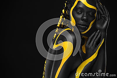 Yellow and black body paint. Woman with face art. Young girl with colorful bodypaint. An amazing afro american model Stock Photo