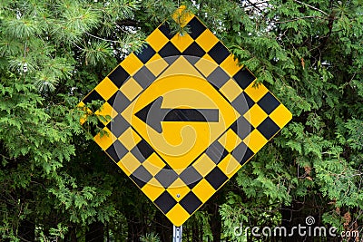 yellow and black checkerboard diamond road caution sign with black arrow pointing left Stock Photo