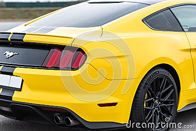 Yellow with black stripes Ford Mustang muscle car in a parking lot. Rear wing view Editorial Stock Photo