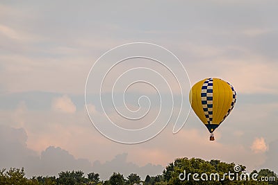 Yellow and blue patterned hot air balloon floats among the mountains in a beautiful sky a at Warren County Farmer`s Fair on 8/1/17 Editorial Stock Photo