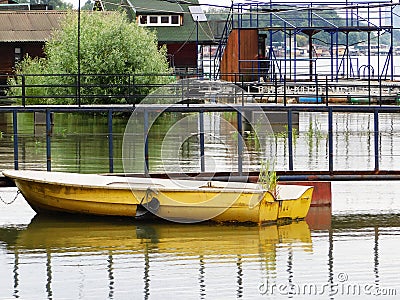 A yellow boat, a deciduous tree and approaches rafts on a swollen river Stock Photo