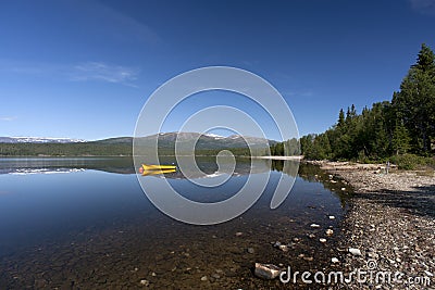 Yellow boat on tranquil lake with snow covered mountains Stock Photo