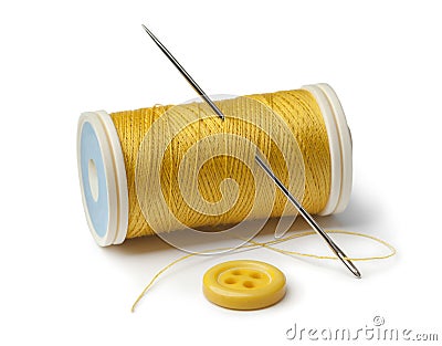 Yellow bobbin, needle and sewing button Stock Photo