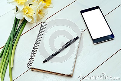 Yellow bouquet of narcissus on white wooden background. Blank card flat lay. Top view on table with narcissus, empty diary, pencil Stock Photo