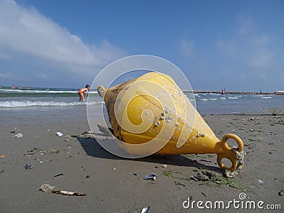 A yellow bouy brought to shore by the sea Editorial Stock Photo