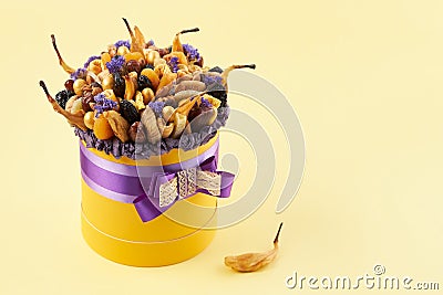 Yellow box with a bunch of dried fruits on a yellow background, copy space Stock Photo