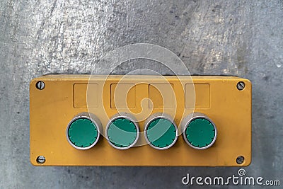 Yellow box with green push button, mounted on a galvanized steel carrier in a work hall Stock Photo