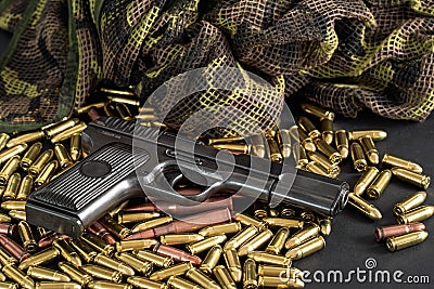 Yellow brass and brown bronze bullets, with black gun near, closeup detail Stock Photo