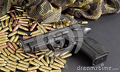 Yellow brass and brown bronze bullets, with black gun near, closeup detail Stock Photo