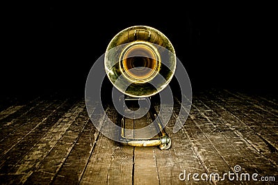 Yellow brass instrument trombone lies on the wooden floor of the stage. front view on the bell Stock Photo