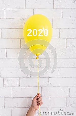 Yellow bright balloon with 2020 white text in woman hand Stock Photo