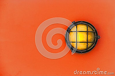 Yellow bulkhead light ship deck lamp on installed on orange color wooden wall background. Stock Photo