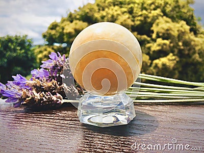 Yellow calcite crystal ball is on a wooden table. Stock Photo
