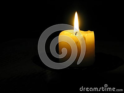 Yellow candle in a dark room Stock Photo