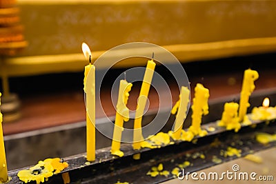 Yellow candles burning at a traditional Thai Buddhist .Thailand. Stock Photo