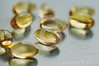 Yellow capsule with vitamin E tocopherol on blue surface Stock Photo