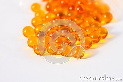Yellow capsules of vitamins lie on a table on a white background Stock Photo