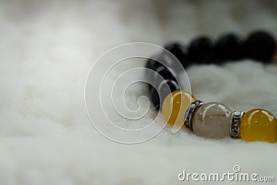 Yellow Chrysoberyl Cat`s Eye stone and Lava stone.Luck fortune stone bracelet with yellow and black tone on white wool background Stock Photo