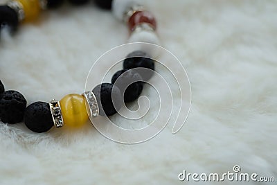 Yellow Chrysoberyl Cat`s Eye stone and Lava stone.Luck fortune stone bracelet with yellow and black tone on white wool background Stock Photo