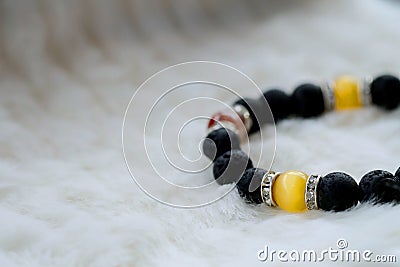 Yellow Chrysoberyl Cat`s Eye stone and Lava stone.Luck fortune stone bracelet with yellow and black tone on white wool background Stock Photo