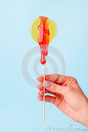 Yellow circle lollypop with droping sugar paste in hand. The concept of intimate depilation - bikini zone, hair removal with hot Stock Photo