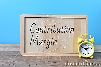 Yellow clock and wooden board written with text CONTRIBUTION MARGIN Stock Photo