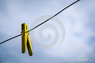 Yellow clothespin hanging on a rope against a cloudy sky Stock Photo