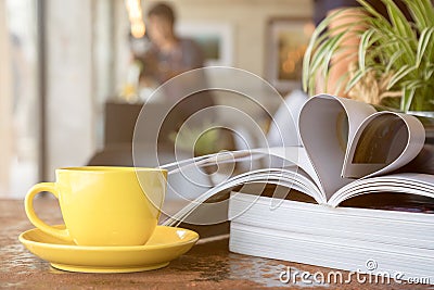 Yellow coffee cup placing together with magazine like Heart Shape Stock Photo