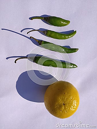 Yellow coloured lemon on white background with chillies. Stock Photo