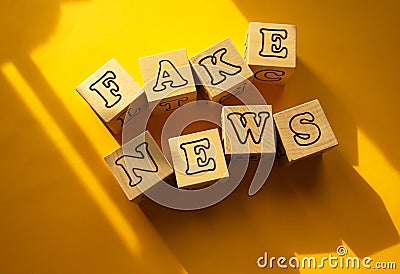 On a yellow background with shadows on the cubes, the inscription is fake news. Stock Photo
