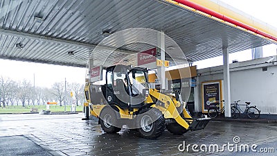 Yellow excavator construction vehicle refueling at a gas station in Germany Editorial Stock Photo