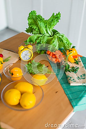 Yellow cooking timer between fresh cooking ingredients - vegetables, lemons and green salad Stock Photo