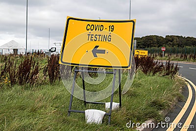 Yellow Covid 19 Test Centre road sign giving directions Stock Photo