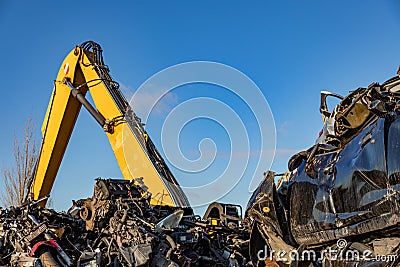 Yellow crane, stacked cars and motors at a dumpsite. Stock Photo