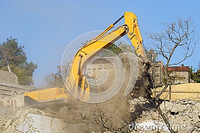 Yellow crawler excavator demolishes dilapidated real estate for future construction of modern house Stock Photo