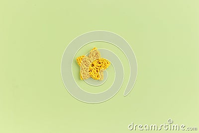 Yellow crocheted flower on a green background Stock Photo