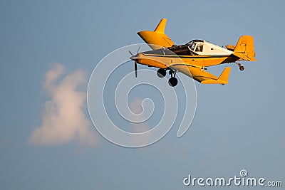 Yellow Crop Dusting Plane Flying in a Blue Sky Stock Photo