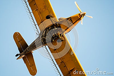 Yellow Crop Dusting Plane Flying in a Blue Sky Stock Photo