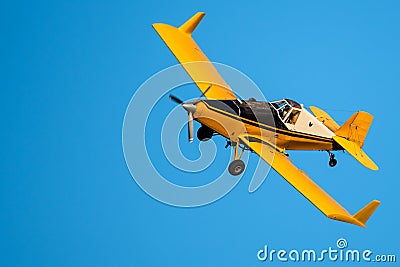 Yellow Crop Dusting Plane Flying in a Blue Sky Stock Photo