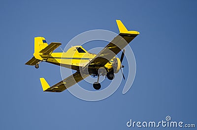 Yellow Crop Dusting Plane Flying in a Blue Sky Stock Photo
