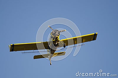 Yellow Crop Dusting Plane Flying in a Blue Sky Editorial Stock Photo