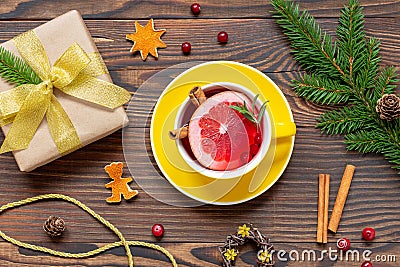 Yellow cup of tea with orange and spices near Christmas present and fir branch Stock Photo