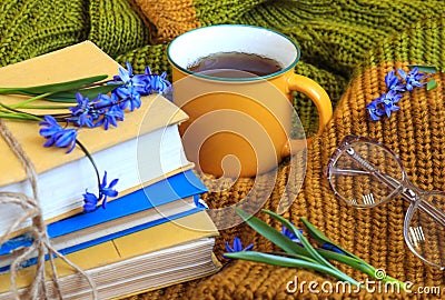 A yellow cup of tea, a stack of books with blue flowers, an alarm clock, glasses for vision on a knitted sweater, a close-up-the Stock Photo