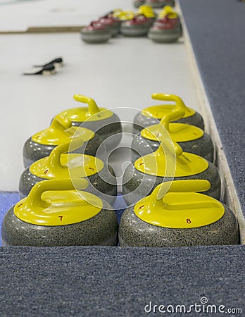 Yellow curling stones on ice Stock Photo
