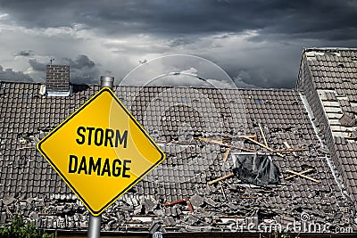 yellow damage warning sign in front of storm damaged roof of house Stock Photo