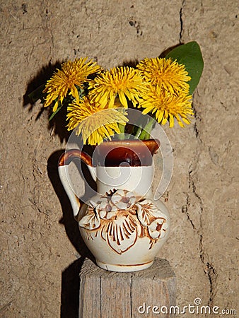Beautiful yellow dandelions in a vase on the table, spring flowers, clear weather. Stock Photo