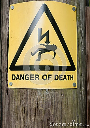 Yellow danger of death sign on wooden post Stock Photo