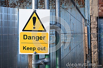 Yellow Danger Keep Out sign on metal fence Stock Photo