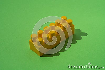 Yellow detail of children`s constructor isolated on green background Stock Photo