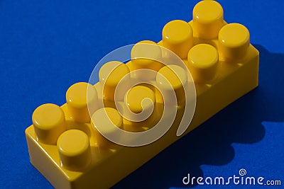 Yellow detail of the constructor on a blue background with hard highlights top view close-up Stock Photo